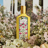 Gucci Flora Gorgeous Orchid Eau de Parfum 100ml displayed among lush garden flowers, emphasizing its luxurious floral scent.