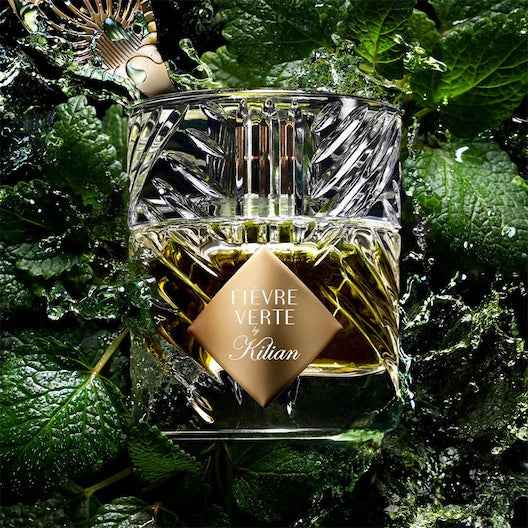 Kilian Fièvre Verte – Eau de Parfum (50ml) bottle surrounded by fresh green mint leaves and water splashes, highlighting its absinthe-inspired freshness.